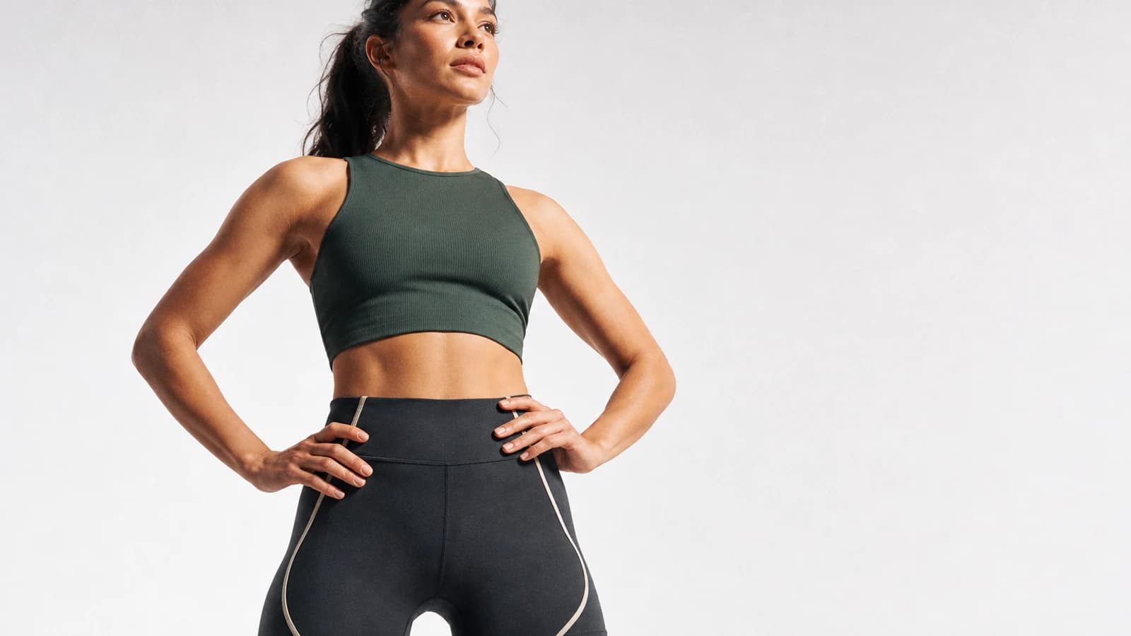 A woman in green athletic clothes standing against a light studio background
