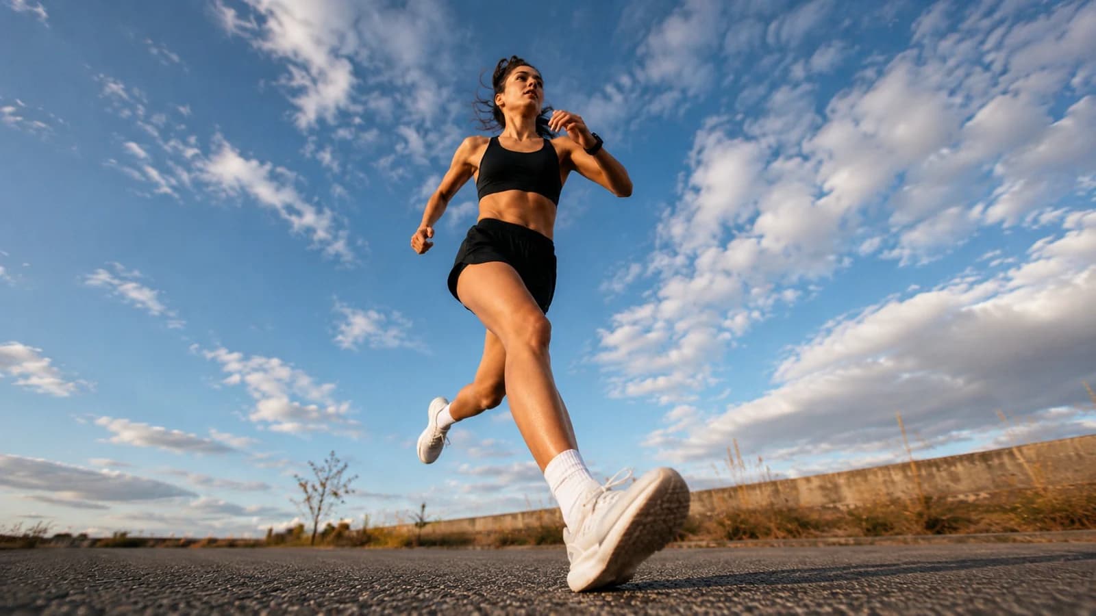 A woman running outdoors on a road under a wide sky